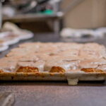 Image of freshly baked cinnamon rolls with biscuit dough, covered in icing, placed on a kitchen counter with a recipe card below.