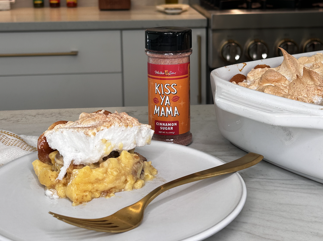 Piece of banana pudding on a kitchen counter, with a bottle of Kiss Ya Mama Cinnamon Sugar placed beside it.